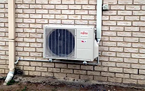 A Fujitsu outdoor unit installed against a rendered wall