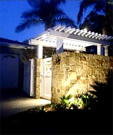 Garden entry with uplights on a stone wall at night