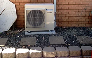 A Panasonic outdoor unit installed on a garden bed pad