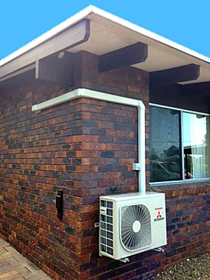 Outdoor split system unit mounted on a brick home with neat, painted conduit